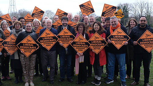 Picture of Lib Dem activists in the field holding Liberal Democrats Winning Here signs